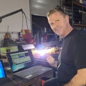 a person using a laptop and plasma cutter